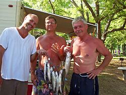 Three men showing off their catch of trout
